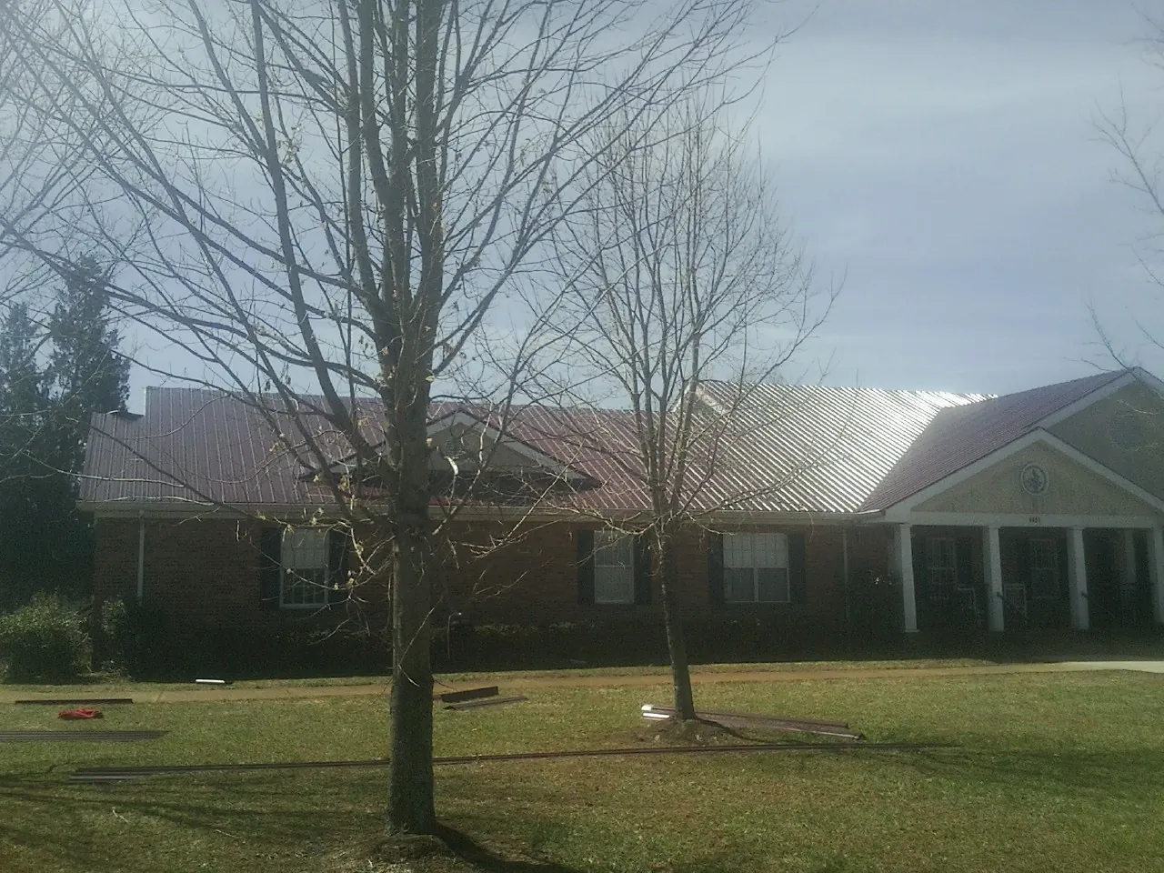Red metal roof on a brick building seen from the front lawn in Kingsville
