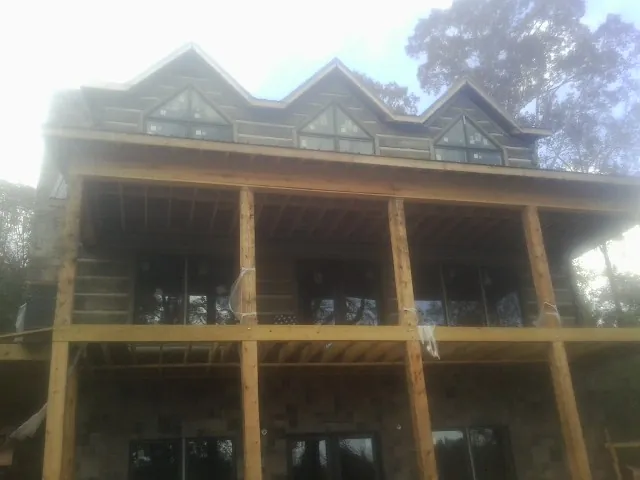 Dormers and porch framing on a large log home under construction — Roof Coating work by our crew in Kingsville