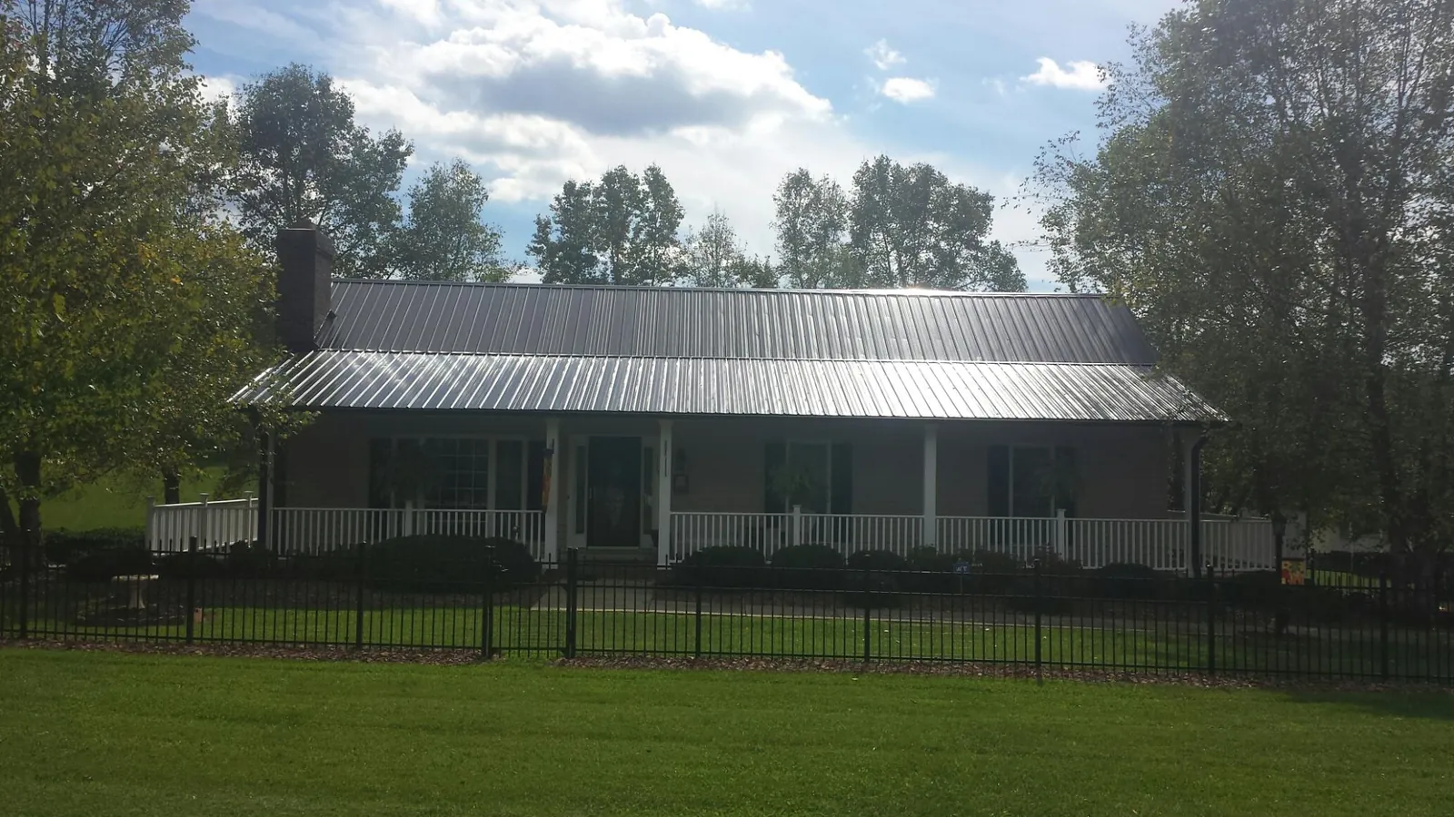 Gray metal roof on a brick ranch with a full width front porch — Gutter Guard Installation work by our crew in Kingsville