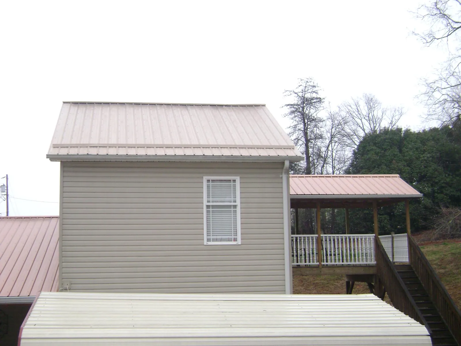 Tan metal roofs on a two story addition and attached porch, from a Roof Replacement job in Kingsville